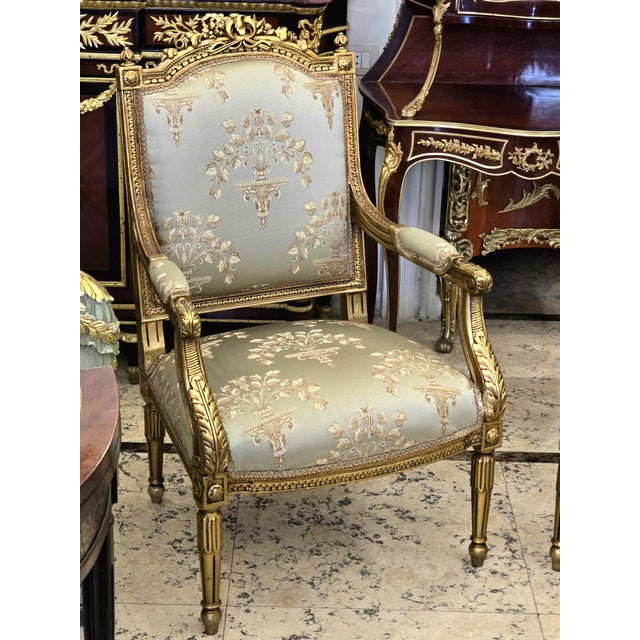 Elegant French-inspired armchair upholstered in a refined beige damask fabric with a delicate floral motif. The structured...