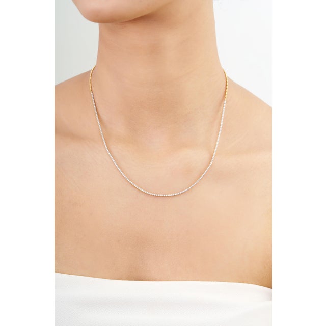This modern tennis necklace features 1.17 carats of round brilliant-cut natural diamonds set in 18k yellow gold. Each...