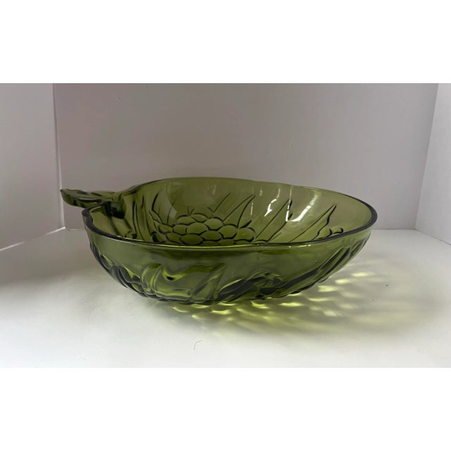 A richly sculptural mid-century pressed glass bowl in a deep olive tone, featuring an abundant grape cluster motif and...