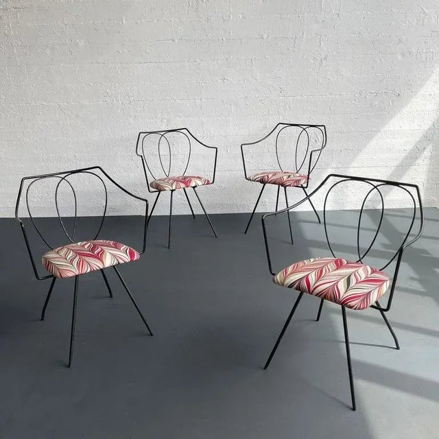 Delicate set of four wrought iron dining armchairs attributed to Tony Paul feature minimal frames with concentric loops as...