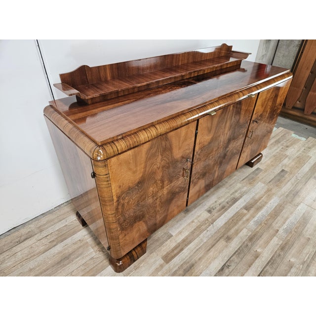 An elegant and impressive 1940s French sideboard, featuring a refined Art Deco style and a splendid walnut veneer,...