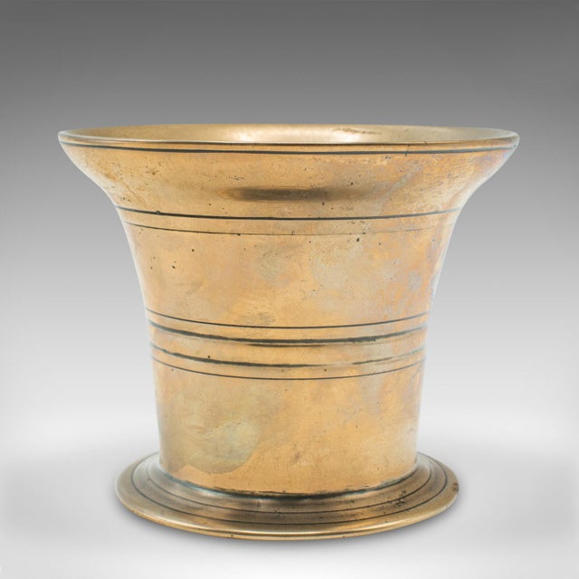 This is an antique mortar and pestle duo. An English, polished brass apothecary dish or decorative jardiniere pot, dating...