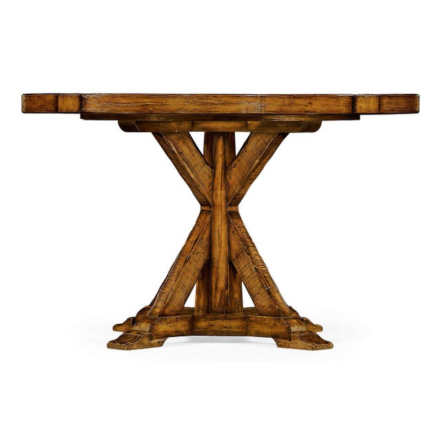 A round dining table finished in a warm walnut color with a rustic finish showing exposed saw marks and set on a bracketed...