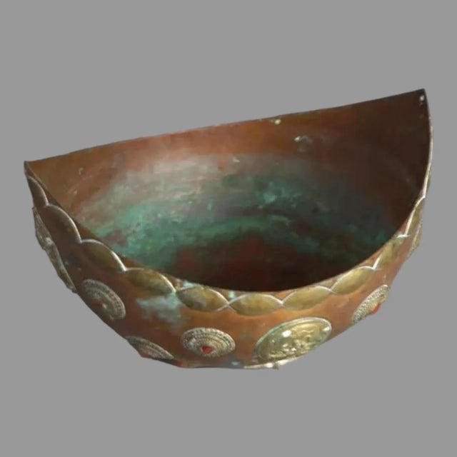 An antique Tibetan ceremonial oblong bowl of copper construction with brass medallions, colored jewels and figural...