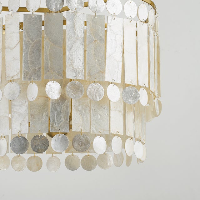Gorgeous layers of Capiz shell, in alternating circles and rectangles, dangle from an Aged Brass frame for a sophisticated...