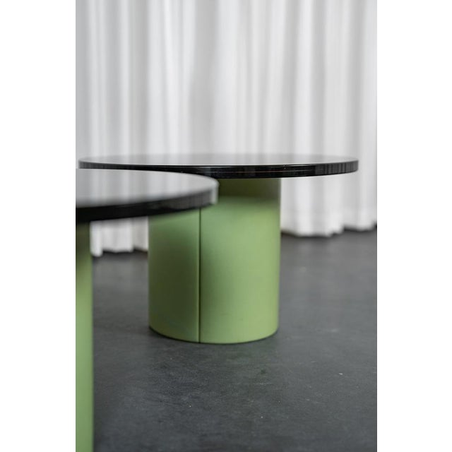 Set of 2 coffee tables composed of a central barrel upholstered in matcha green leather and a thick smoked acrylic glass...