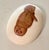 This vintage ceramic paperweight, shaped like an oval egg. features a detailed brown ink illustration of a barred owl...