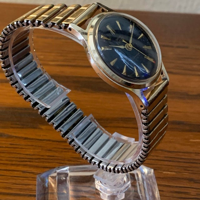 Vintage Smiths Empire Shockproof 5 Jewels mechanical wristwatch featuring a handsome black textured dial with gold-tone...