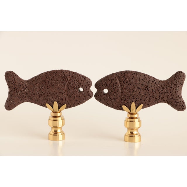 Pair of lamp finials crafted from copper brown lava stone fish topping golden brass bases sized to fit a lamp with a...