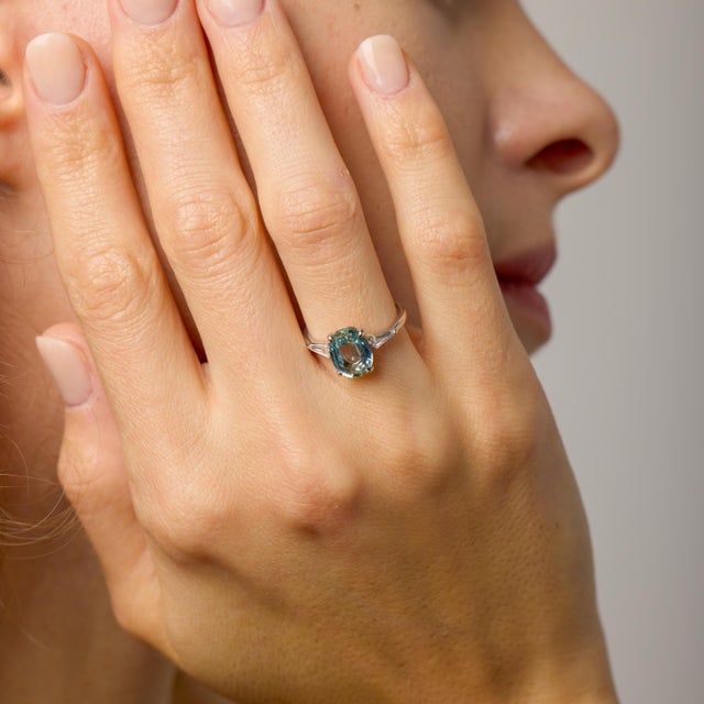 This contemporary engagement ring is a refined celebration of color, geometry, and modern craftsmanship. At its center...