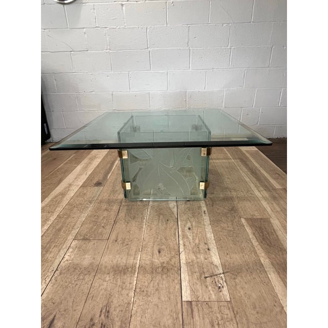A striking postmodern coffee table featuring a sculptural architectural base composed of acid-etched glass panels adorned...