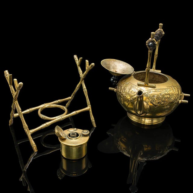 This is an antique spirit kettle. An English, brass teapot on stand with fuel burner, dating to the late Victorian period,...