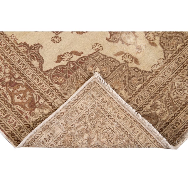 Antique Tabriz hand-knotted wool rug with a tan field. This piece has an ivory accents all-over floral design. This rug...
