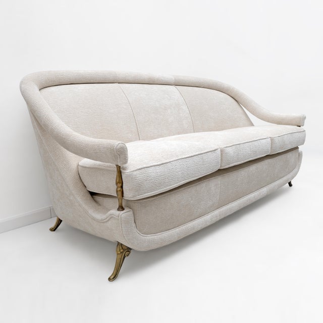 An elegant french sofa from the 1950s, featuring a soft, enveloping silhouette inspired by art deco aesthetics. in...