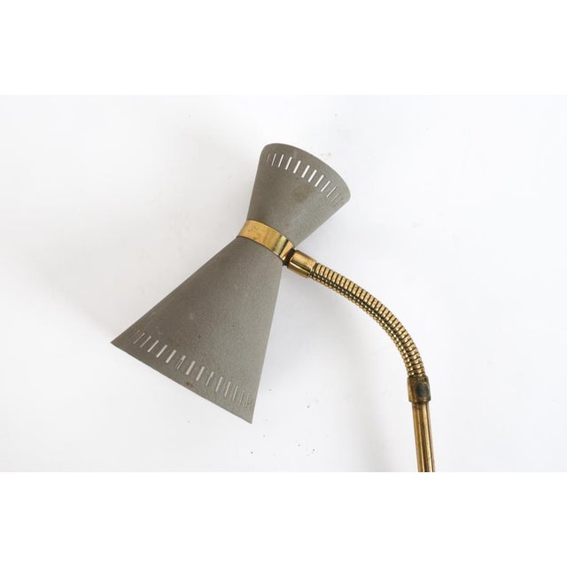A Swedish brass arm and a gray metal shade lamp by Falkenbergs Belysning. The shade is perforated at the top and bottom to...