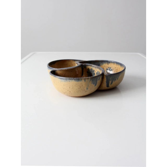 A vintage studio pottery bowl, hand-crafted with a divided form featuring three compartments. The surface is finished in a...