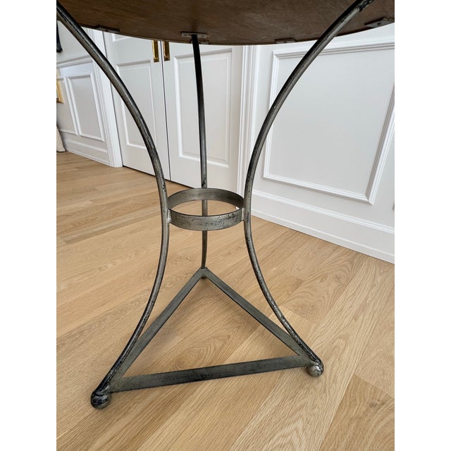 French mid-century guéridon side table featuring a sculptural hand-forged silver iron base with original aged zinc-washed...