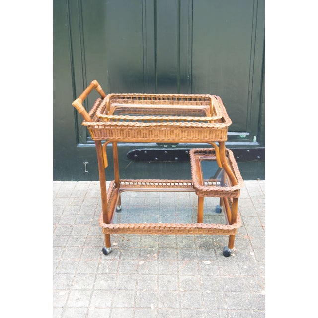Vintage rattan and wicker bar cart or tea cart. Three levels with glass shelves. Top surface is a removable glass and...