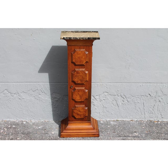 A mid century beautifully made display pedestal with marble top, exotic wood embellishments, and front opens to reveal a...