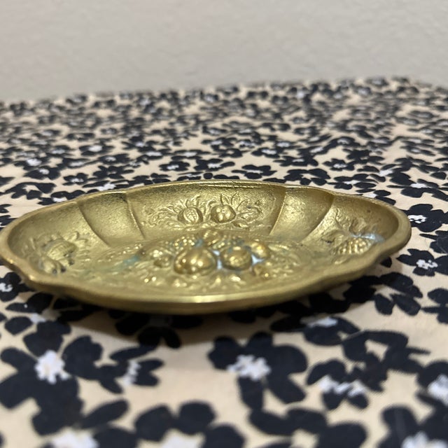 Exhibiting the intricate charm of early to mid-century metalwork, this oval brass dish features a striking repousse...