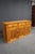 Pine sideboard featuring three drawers above three paneled cabinet doors, with a warm honey-colored finish and pronounced...