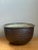 This vintage monumental rustic ceramic bowl is crafted from stoneware and finished in a rich brown glaze that softly...