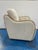 Stylish Modern swivel chair with wood trim arms, upholstered with a nubby cream fabric. Showroom floor sample.