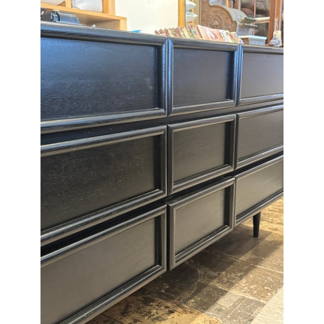 Black dresser with mid-century modern style. Featuring nine drawers in varying sizes, tapered legs, dovetail joinery and a...