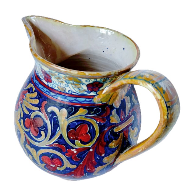 Vintage hand-painted Etruscan style gryphon and soldier pitcher with handle and spout.Hand-painted images of a framed...
