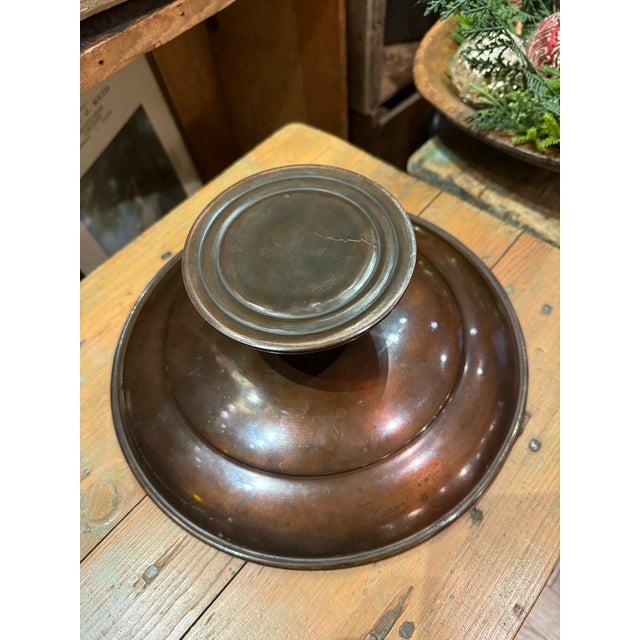 A striking antique bronze centerpiece pedestal bowl featuring a detailed hunting-themed design. The bowl and base display...