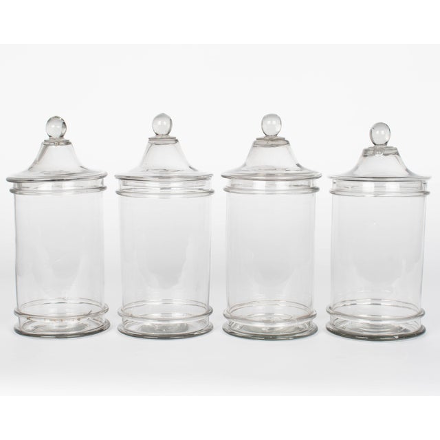 A set of four French hand-blown glass lidded apothecary, or candy jars. Smooth canister form with knob on lid. Perfect for...