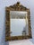 Beautiful antique mirror in carved wooden frame with gold leaf finish and a crest on the top. The mirror can be hung...