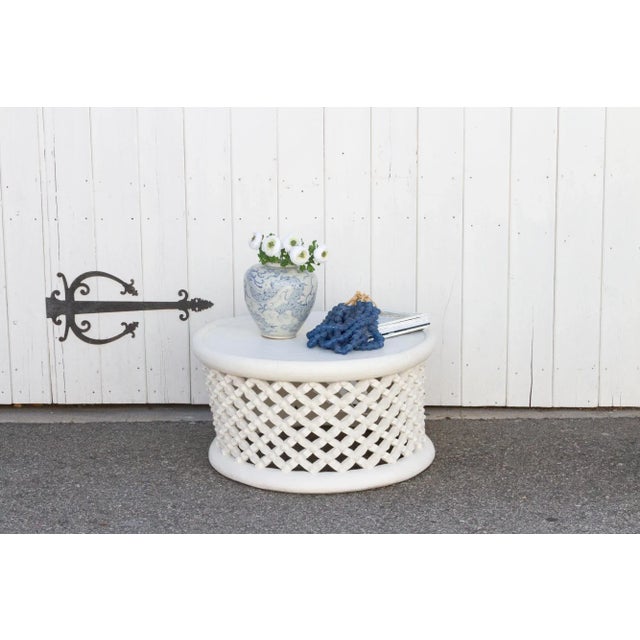 Crafted from a single hollowed out tree trunk, this round coffee table features a intricate tribal spider web like pattern...