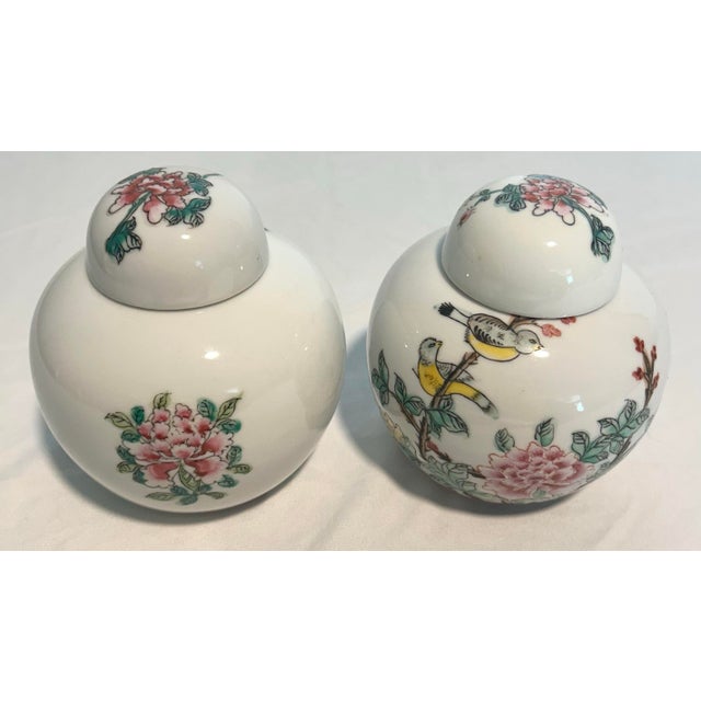 An elegant pair of porcelain ginger jars from Neiman Marcus, featuring delicate floral and bird motifs inspired by...