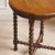 A historic round side table made of oak, circa 1900, with a turned base and cross-linked struts. Its compact height,...