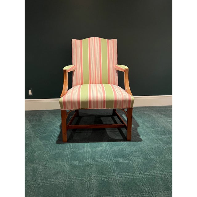 A handsome English Georgian arm chair has a warm patina to the mahogany wood. The style creates a classic and refined look...