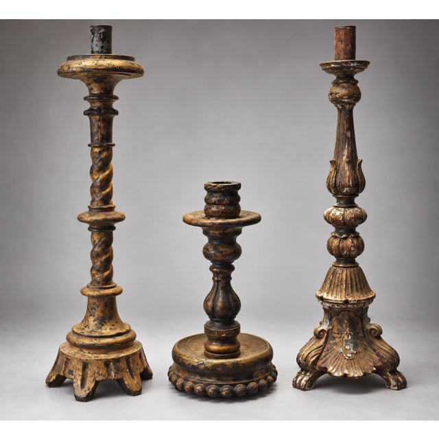 A collection of three antique hand-carved wooden candlesticks featuring ornate turned columns, scalloped bases, and...