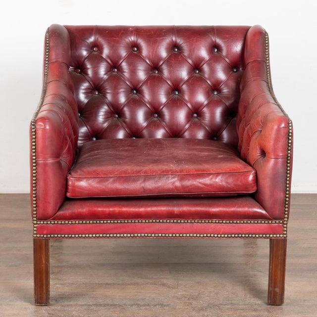 20th Century vintage square club chair upholstered in red leather. This handsome chair features a tufted button back and...