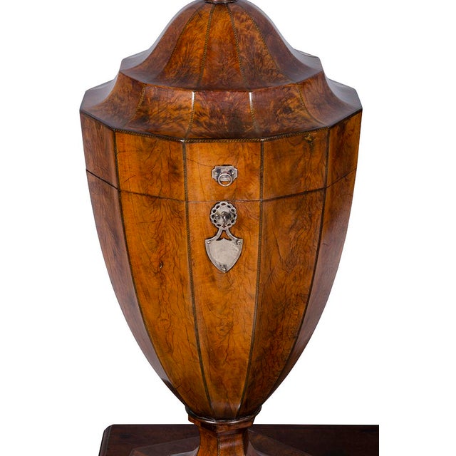 Urn form with arched cover with carved finial opening to expose cutlery slots, well figured mahogany with mellow brown...