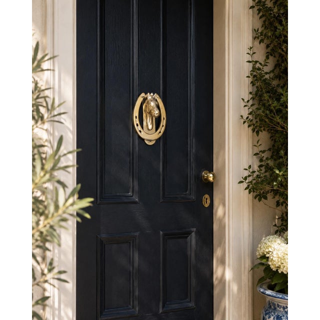 A handsome vintage cast brass door knocker featuring a sculptural horse head framed within a classic horseshoe. The...