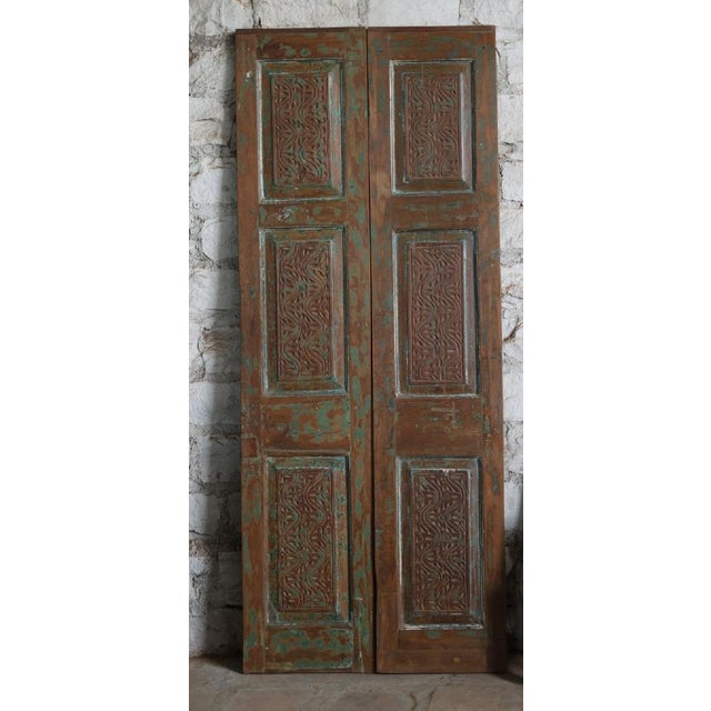 These antique double wooden doors showcase exquisite artisan hand-carving paired with a richly distressed green finish...