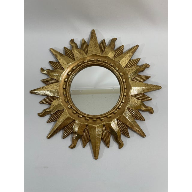 A very brightly gilded gold 13" Sunburst Wall Mirror, circa 1970s-90s. This fabulous celestial mirror features a notched...