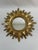 A very brightly gilded gold 13" Sunburst Wall Mirror, circa 1970s-90s. This fabulous celestial mirror features a notched...