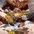 This oil painting captures a serene moment in nature, depicting a gentle stream cascading over smooth stones, surrounded...