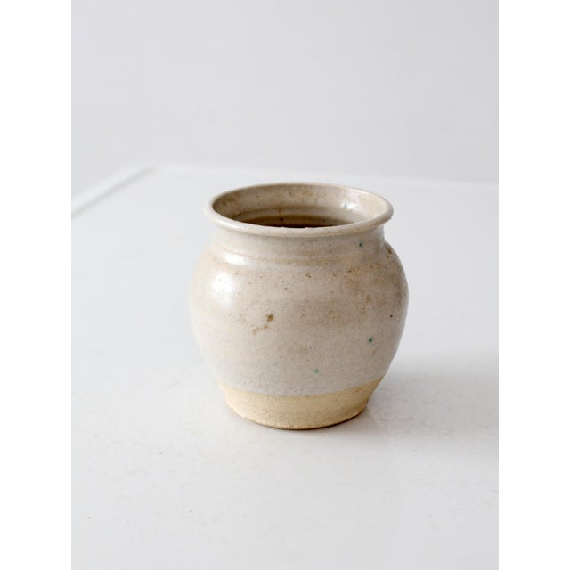 This vintage handmade studio pottery vase features a rounded hand-thrown form with a soft creamy glaze, exposed clay foot,...