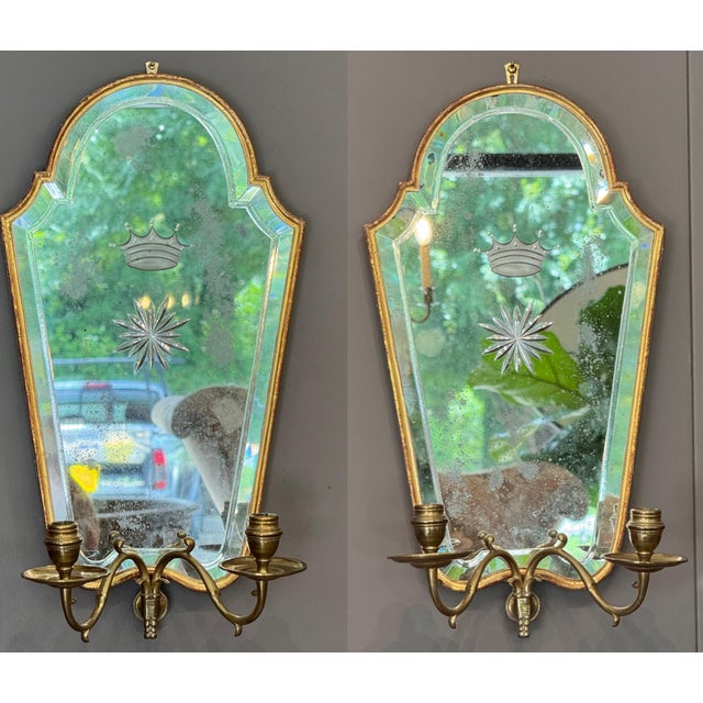 Pair of 20th C. Italian giltwood mirrored sconces, the shaped arched plates with beveled borders, each etched with a...