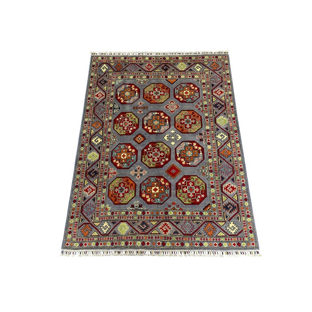 This Philpa Bokhara design wool rug features twelve repeating elephant foot motifs across a slate blue-gray field. Rich...
