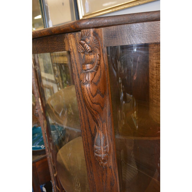 This is a nice looking oak display cabinet. Paw feet in front & carved lion heads on either side. It has a key & locks....