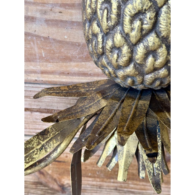 This delightful Mid-20th Century metal tole wall sconce features a sculptural pineapple design, a symbol of hospitality...
