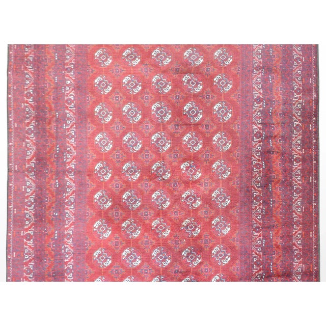 A beautiful 20th century Afghani Turkoman rug with a repeated circular pattern woven in crimson, orange, white and indigo...